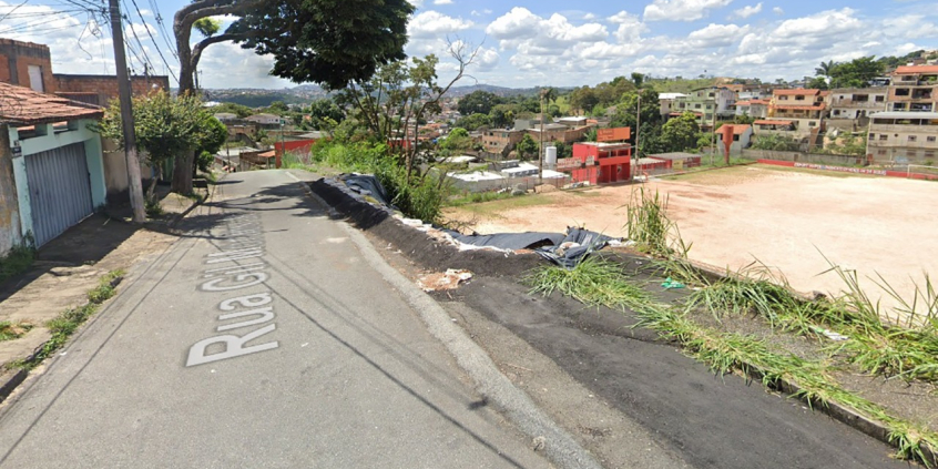 Rua residencial à esquerda e campo de futebol à direita, em nível inferior. Entre a rua e o campo, uma área sofreu contenção de desabamento.