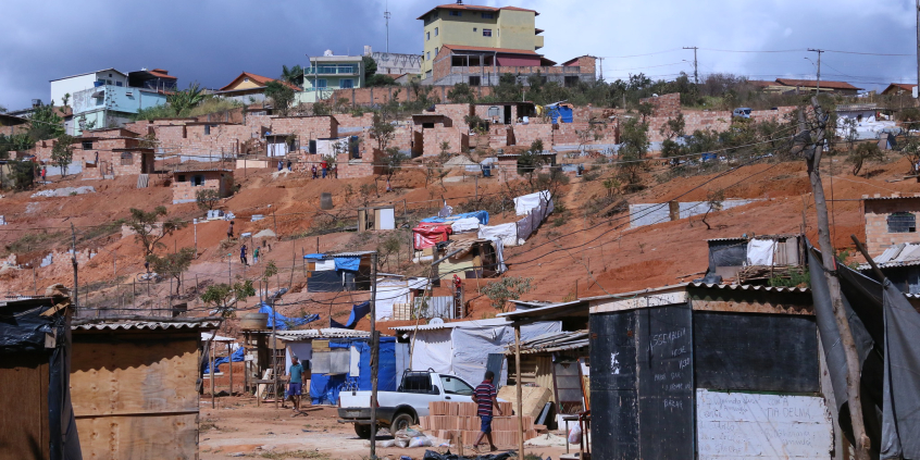 Imagem de um morro com dezenas de casebres com tijolos aparente. a via é de terra