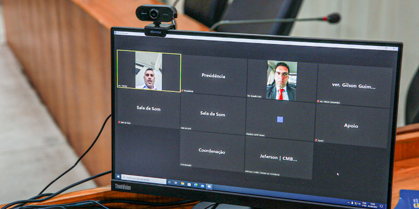 Dois homens participam de reunião remota, exibida em tela de computador.