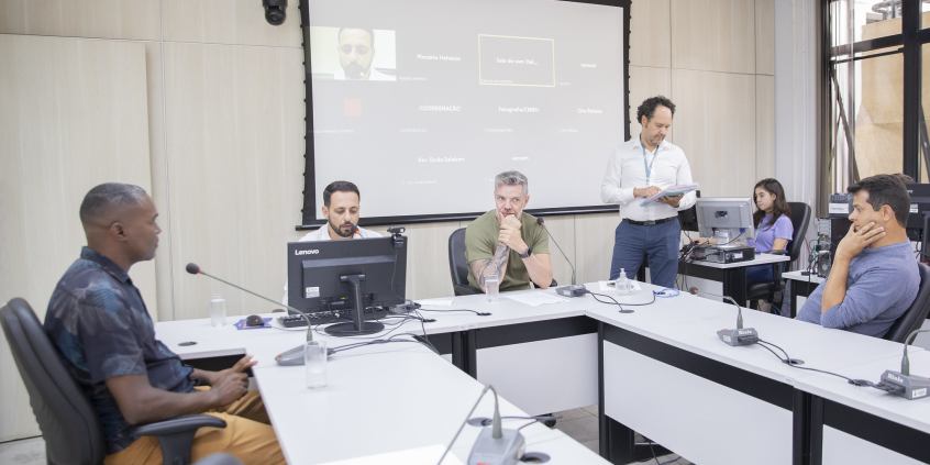 Quatro vereadores em reunião presencial, sentados à mesa, acompanhados de dois assessores da Câmara.