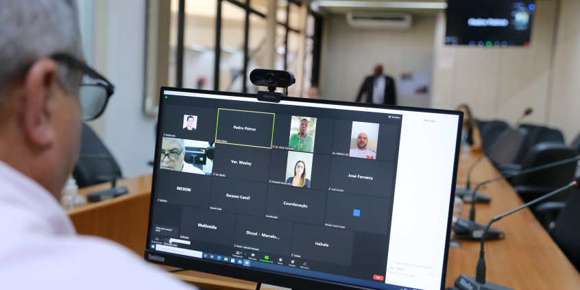 Vereador, sentado à frente de computador, observa a sua imagem e de outros  quatro vereadores em plataforma virtual para reunião remota.