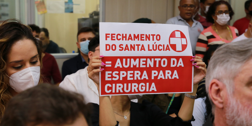 Ao lado de outra mulher, cidadã mostra cartaz com os dizeres: "Fechamento do Santa Lúcia = aumento de espera para cirurgia"