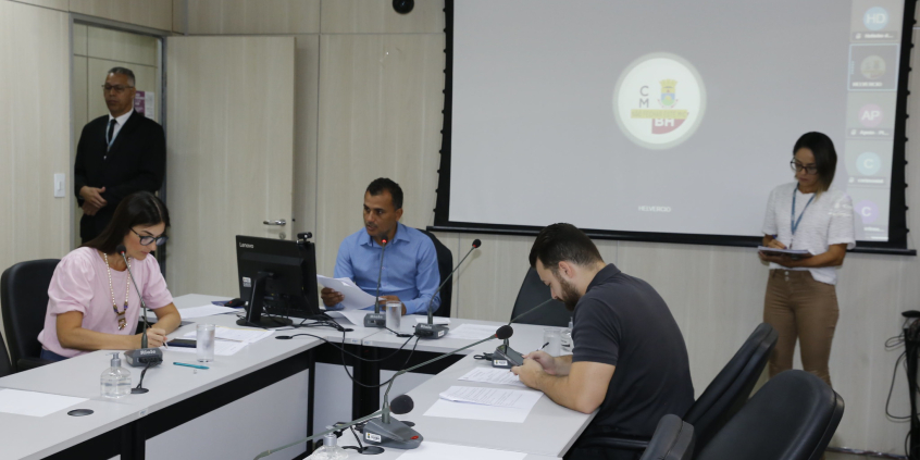 Três vereadores participam de reunião, sentados à mesa.