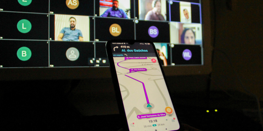 Em primeiro plano, há um celular que mostra a rota disponível em um aplicativo