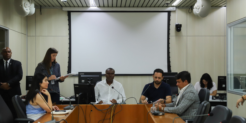 Três vereadores participam de reunião, sentados à mesa.