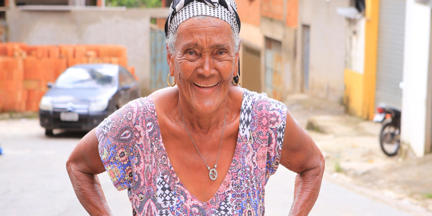 Idosas sorri, de pé, durante o dia, em região carente.