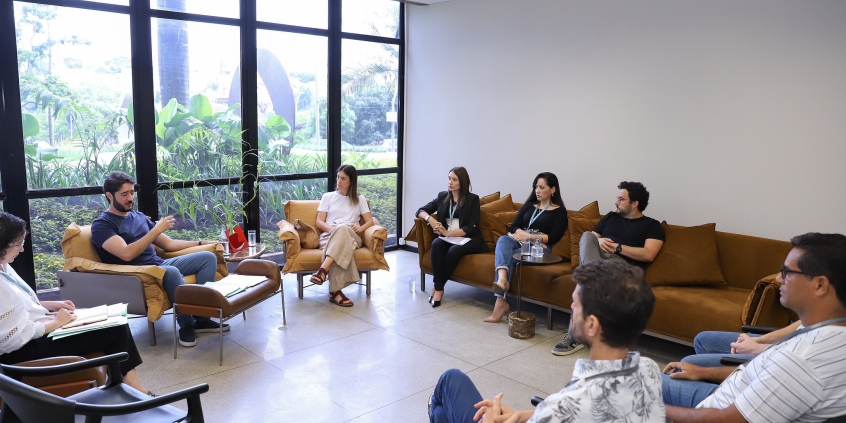O presidente da Câmara, Gabriel, a vereadora Fernanda Pereira Altoé, assessores e servidores sentados em círculo, em reunião na sala da presidência