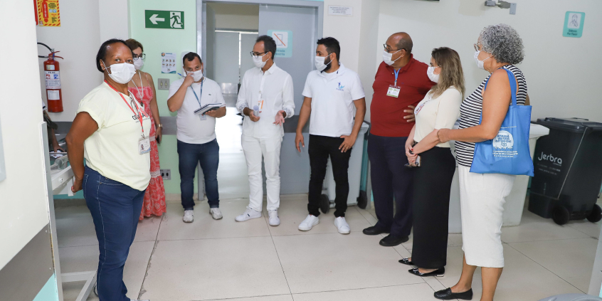 Oito pessoas de pé, reunidas no interior do Hospital Metropolitano Odilon Behrens, durante o dia.
