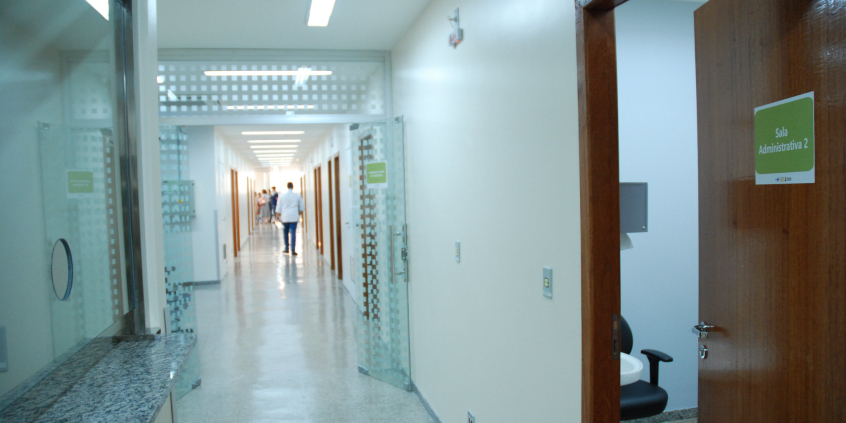 Corredor de posto de saúde, com homem de costas ao fundo 