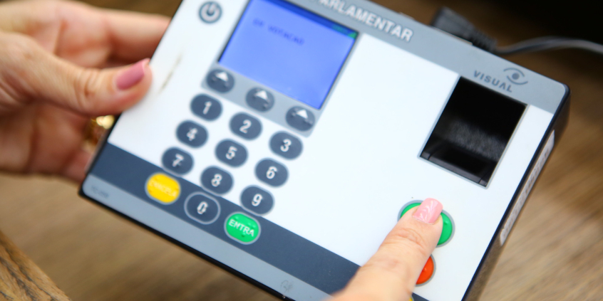 close nas mãos de parlamentar registrando voto em reunião plenária