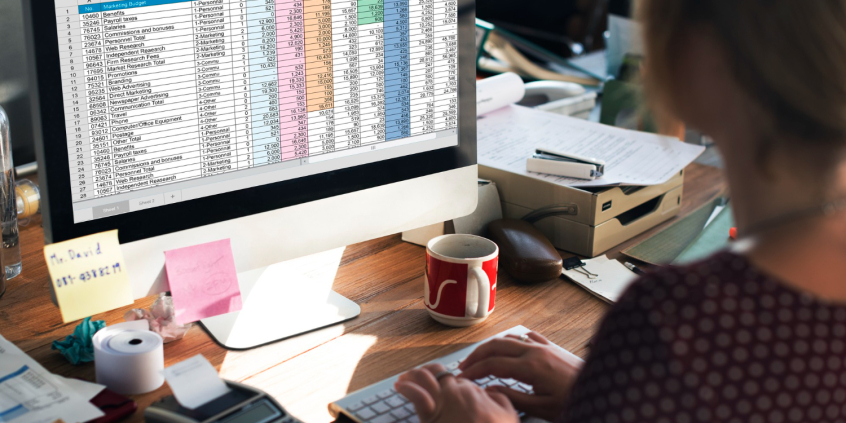 Mulher avalia tabelas financeiras em tela do computador