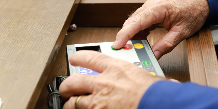 mãos de parlametar operando terminal de votação