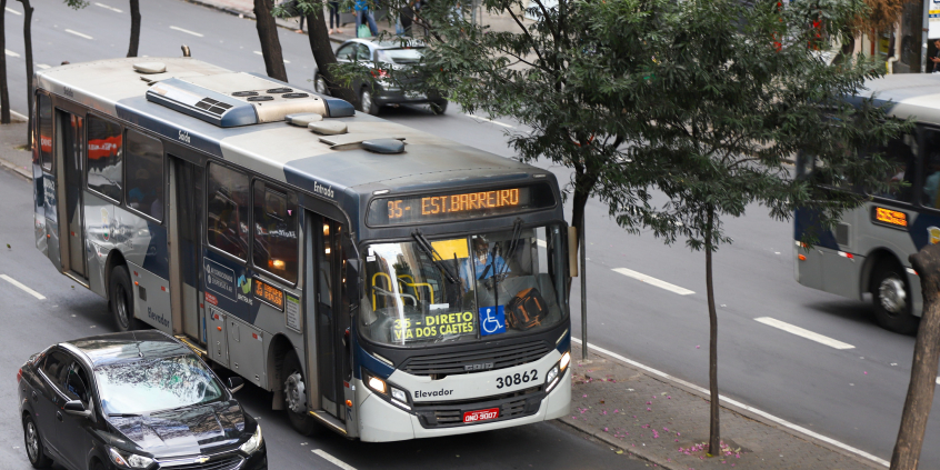 ônibus e automóvel trafegando em via pública