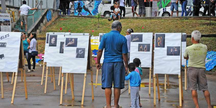 Adultos e crianças observam obras de arte em espaço público