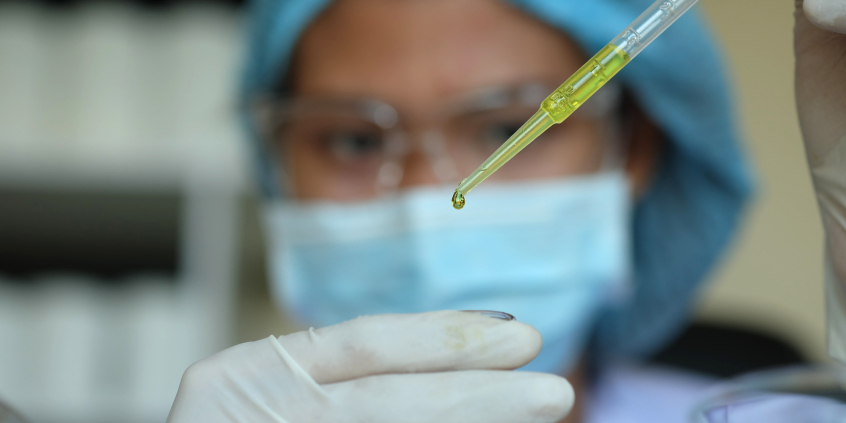 Profissional de saúde de máscara pinga sangue em recipiente