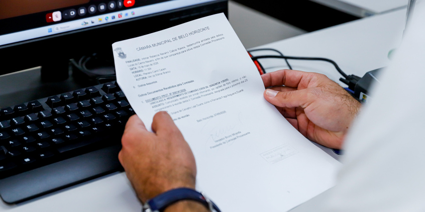 Mão de vereador segurando a pauta da reunião da comissão