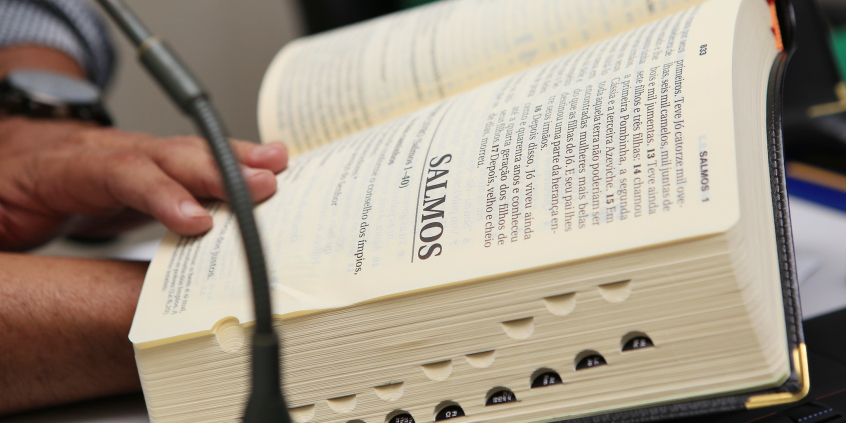 Homem segura Bíblia aberta no início do livro de Salmos