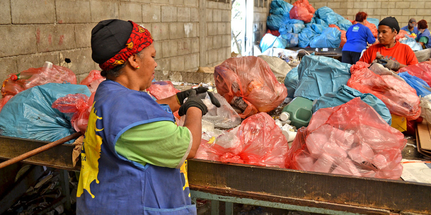 Mulher em frente a sacos de lixo reciclável