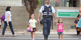 Guarda Municipal ajudando duas crianças a atravessar a rua