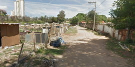 Rapazes caminham em rua de terra entre os barracos da Vila Felicidade, no Bairro Clafate