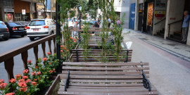 Calçada para pedestres e área de parklet com banco em madeira e flores