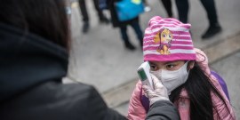 criança com máscara tem temperatura corporal aferida