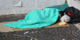 homem dormindo na rua coberto com uma manta verde