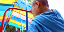 Criança em brinquedo infantil, ao ar livre, durante o dia