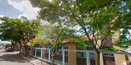 Fachada do Centro de Saúde Betânia, com sete janelas e cinco árvores à frente, durante o dia. 