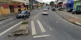 Rua de mão dupla com sinalização falha de faixa de pedestre, durante o dia.