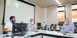 Três vereadores em reunião presencial, sentados à mesa. 