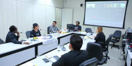 Imagem da sala durante a audiência com os participantes sentados em uma mesa em formato de U