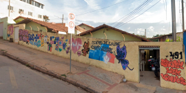 Fachada do Centro de Saúde Campo Alegre, com borboletas, coração e outras imagens coloridas pintadas em muro amarelo, durante o dia.