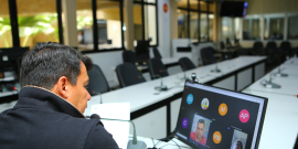 Vereador, sentado em frente ao computador, participa de reunião virtual e olha para tela com a imagem de dois outros parlamentares.