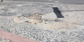 a imagem mostra uma calçada portuguesa com reparo mal feito. é possível identificar o desnível e também terra na parte que deveria estar restaurada