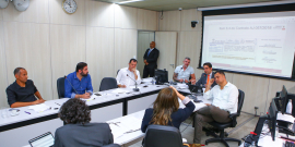 Imagem de participantes em torno da mesa. 