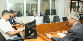 Quatro homens reunidos, sentados à mesa