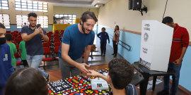 O presidente da CMBH, Gabriel (sem partido) , cumprimenta o mesário. Ao lado, um aluno vota na urna eletrônica do TRE