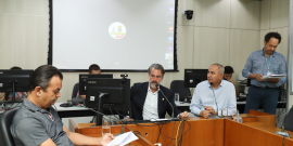 Três vereadores participam de reunião, sentados à mesa.