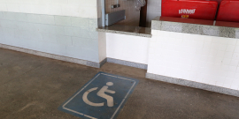 Imagem do símbolo de cadeirante marcada no chão para identificar balcão de atendimento