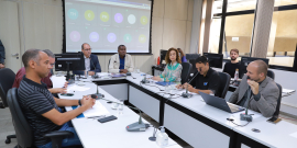 Seis homens e uma mulher reunidos, sentados à mesa