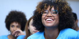 Duas garotas negras e uma branca, sorrindo