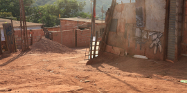 rua sem asfalto rodeada por casas sem reboco, durante o dia.