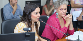 Imagem das vereadoras Marcela Trópia (Novo) e Cida Falabella (Psol) sentadas à mesa , durante reunião da Comissão
