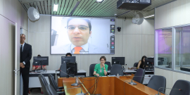 Vereador é exibido em telão de sala de reuniões, presidindo reunião de forma remota.