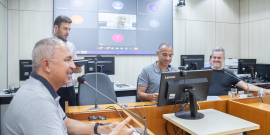 Três parlamentares reunidos, sentados à mesa.