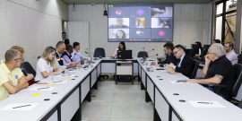 Dez homens e mulheres reunidos, sentados à mesa