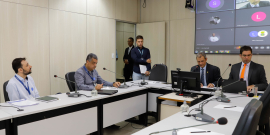 Imagem da reunião com os participantes sentados em volta da mesa em formato de U