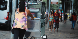De costas, pipoqueira anda em rua movimentada da cidade, durante o dia