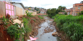 vista de córrego com despejo de resíduos em ambiente urbano